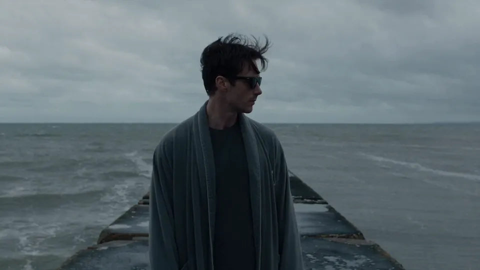 A man in sunglasses on a windy pier